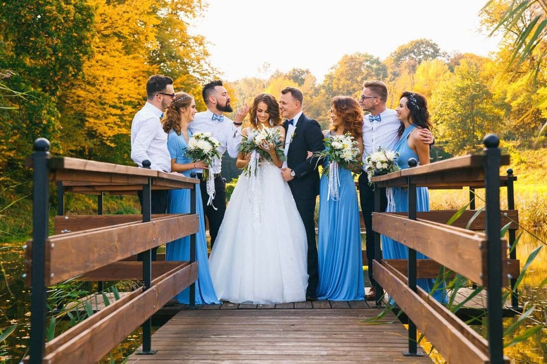 Happy wedding party standing on bridge