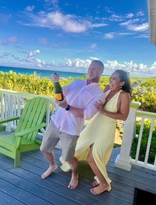Ted and Katy celebrate their Bahamas beach engagement with champagne, laughter, and barefoot joy.